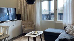 A modern living room with a television, sofa, and a dining area. - Spa Hotel Red Aparments (Kuopio)