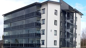 A modern multi-story building with a mix of glass and concrete facades, featuring balconies and a staircase on the right side. - Spa Hotel Red Aparments (Kuopio)