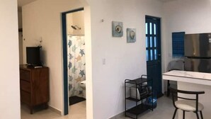 A compact living space with a kitchenette, a dining area, and a small bathroom.