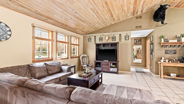 A living room with a wooden ceiling, a large TV, a sofa, and a bear mounted on the wall. - Northwoods Oasis close to Duluth - BOULDBERBELLE RETREAT (Saginaw)