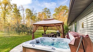 A hot tub with a wooden exterior, a pergola, and a dining area with outdoor furniture. - Northwoods Oasis close to Duluth - BOULDBERBELLE RETREAT (Saginaw)