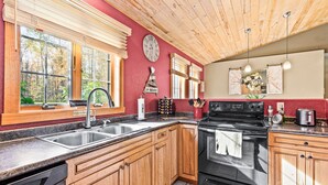 A kitchen with wooden cabinets, a black stove, and a sink. - Northwoods Oasis close to Duluth - BOULDBERBELLE RETREAT (Saginaw)