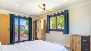 Un dormitorio con cama, armario, ventilador de techo y ventana con cortinas.