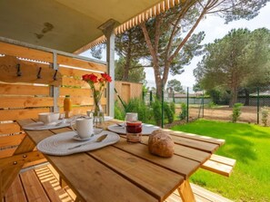 A wooden table set for dining with a view of a grassy area and trees.