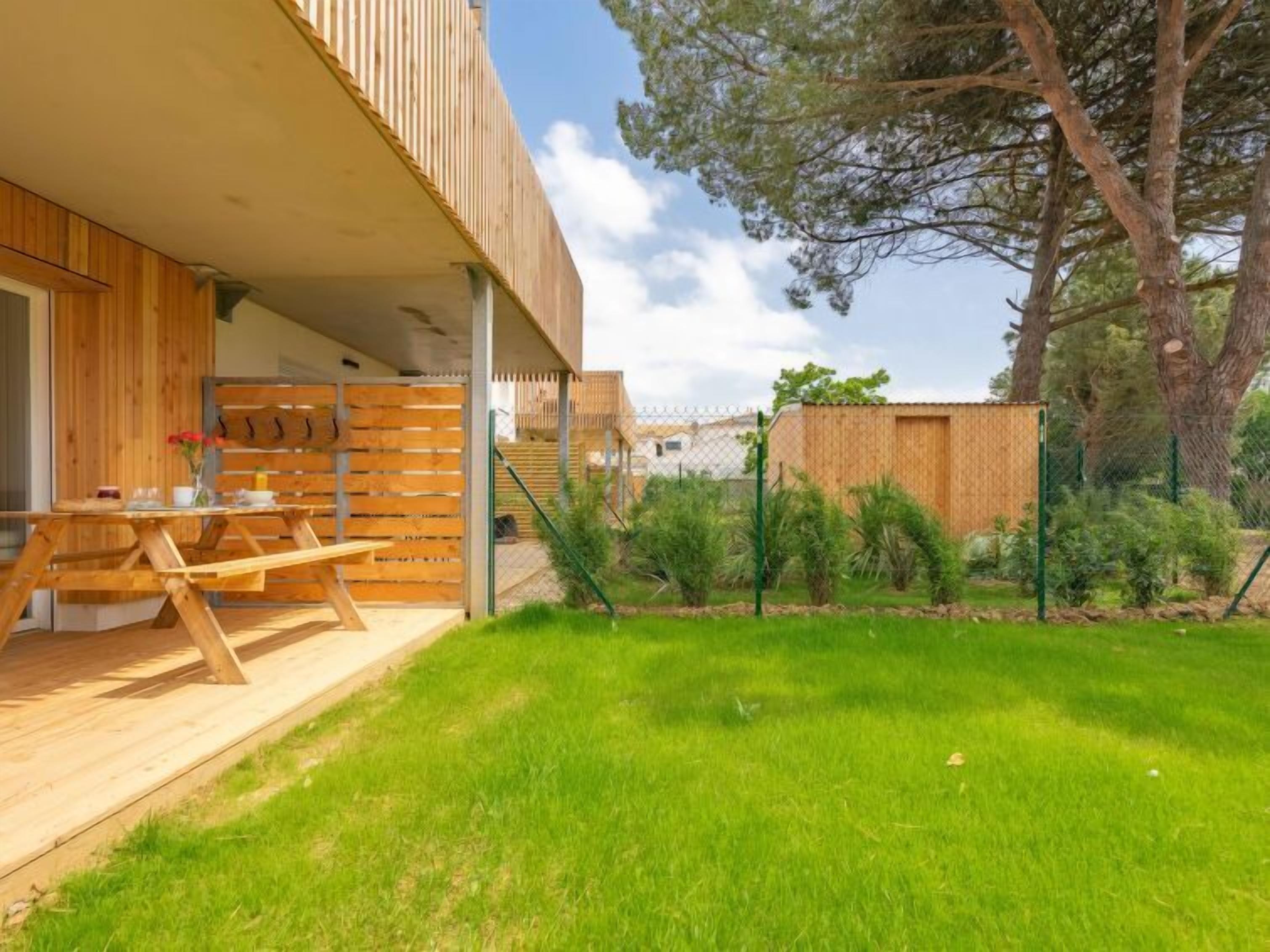 Una casa moderna con terraza de madera, mesa de comedor y zona exterior cubierta.
