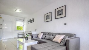Un salon moderne avec un canapé d’angle gris, une table basse blanche et deux œuvres d’art encadrées accrochées au mur.