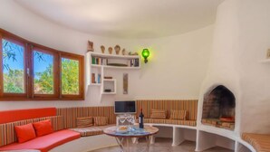 A cozy living area with a curved sofa, a small round table, and a fireplace. - Es Pujols by Interhome (Es Pujols)