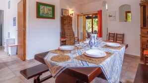 A dining area with a table set for four, wooden chairs, a patterned tablecloth, and a cabinet with a mirror. - Es Pujols by Interhome (Es Pujols)