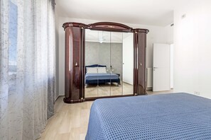 A bedroom with a bed, a wardrobe, and a mirror.