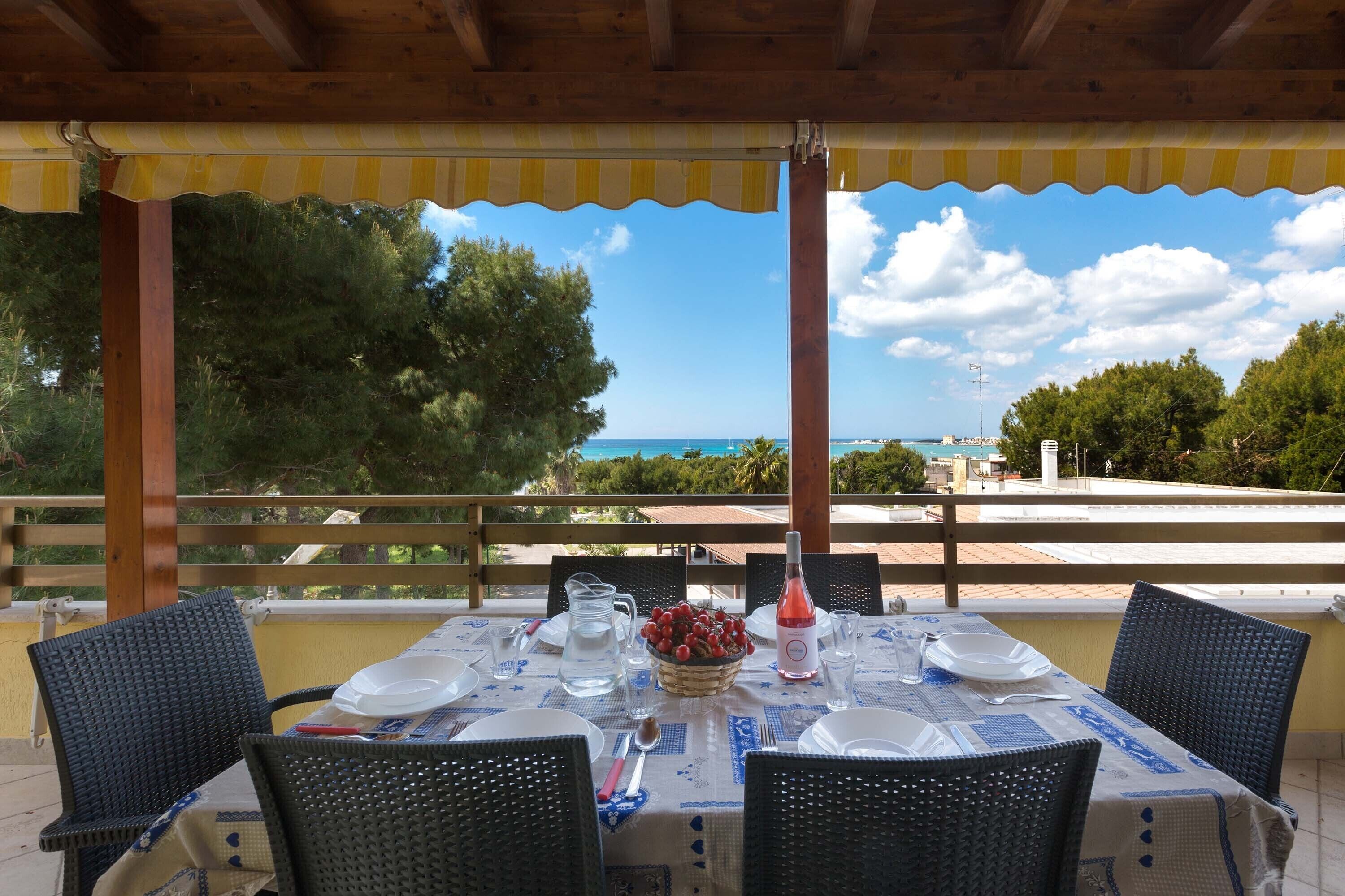 An outdoor dining area with a table set for four, a pitcher, and a basket of fruit.