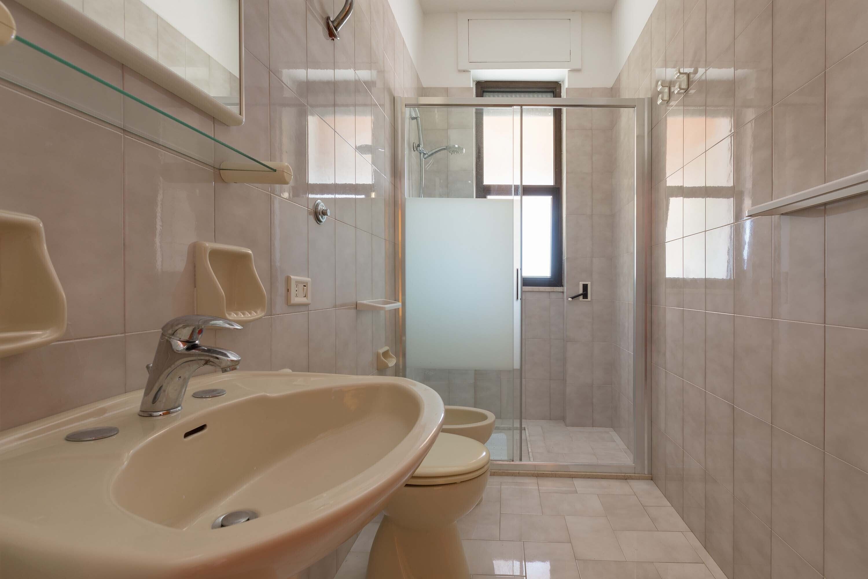 A bathroom with a sink, toilet, and glass-enclosed shower.