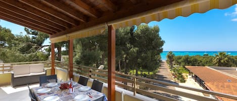 A covered outdoor dining area with a table set for four, overlooking a coastal landscape.
