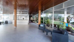 Eine geräumige Lobby mit einer Rezeption, einer Sitzecke und großen Fenstern mit Blick ins Freie.