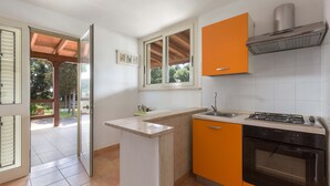 Una cocina con estufa a gas, horno y armarios color naranja.
