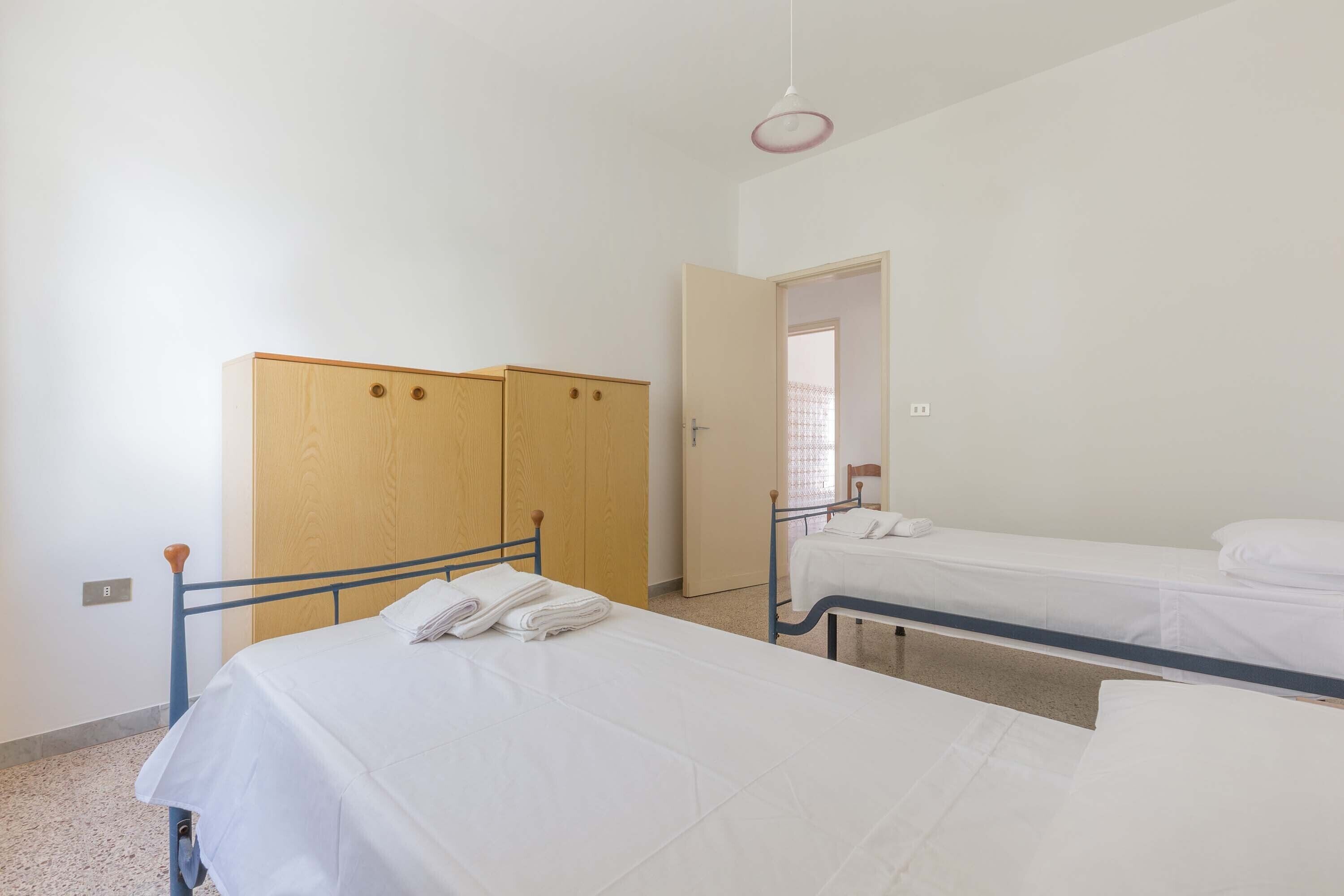 Una habitación con dos camas individuales, un armario y una puerta que da a otra estancia.