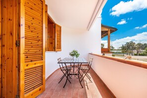 Un balcone con una porta in legno, un tavolo con sedie e una pianta in vaso.