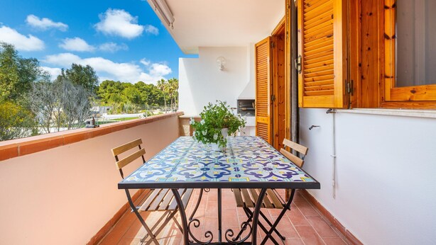 Un balcón con una mesa y sillas de baldosas, y una planta en maceta.