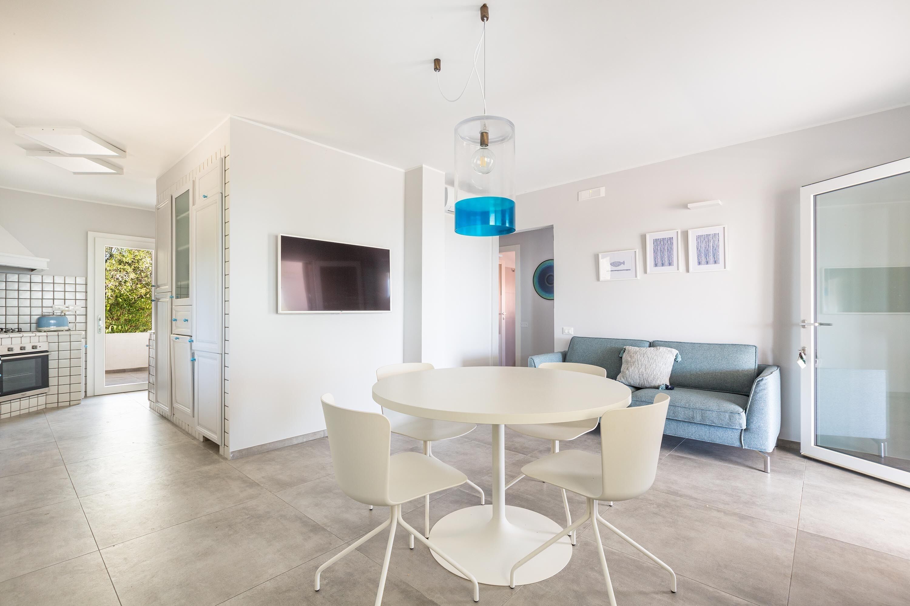 A modern kitchen with a built-in oven and a dining area with a round table and four chairs.