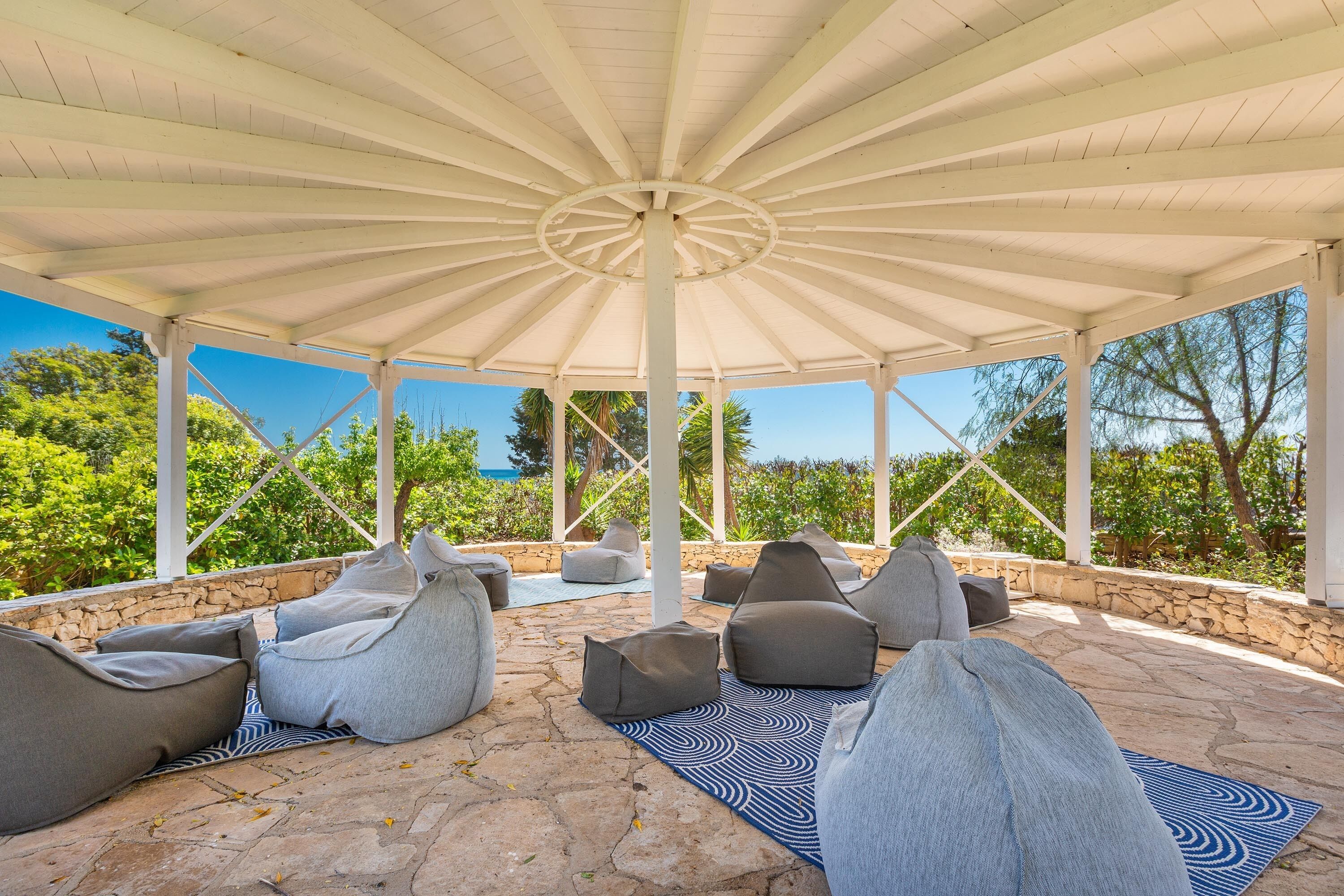 A covered outdoor seating area with stone flooring and grey bean bag chairs.