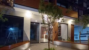 A modern building with a reception desk, a small tree, and a number '220' sign.