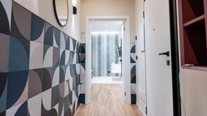 A hallway with patterned walls, a door leading to a bathroom, and a mirror on the wall. - Calvani 23 Luxury House (Bari)