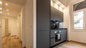 A modern kitchen with grey cabinetry, a built-in oven, and a window providing natural light. - Matilde Modern apartment (Rome)