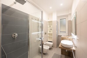 A modern bathroom with a glass shower enclosure, a wooden vanity, and a toilet.