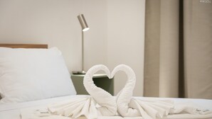 A neatly made bed with white linens and a heart-shaped towel arrangement. - Matilde Modern apartment (Rome)