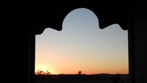 A sunset view through a window with a decorative arch. - Luxury  Saf Saf Camp (Taouz)