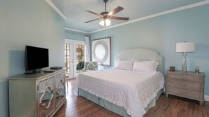 Ein Schlafzimmer mit Bett, Fernseher, Kommode und Deckenventilator.