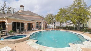 Une piscine avec un jacuzzi, des chaises longues et un patio couvert.