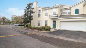 Une rue résidentielle bordée de maisons à deux étages, avec une porte verte et une porte de garage blanche.