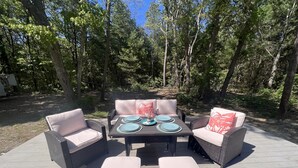 Eine Terrasse im Freien mit Korbmöbeln, darunter zwei Sofas und ein Tisch mit Tellern und einem Glas.