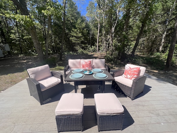 Eine Terrasse im Freien mit Korbmöbeln, darunter zwei Sofas und ein Tisch mit Tellern und einem Glas.