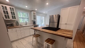Eine moderne Küche mit weißen Schränken, einem Edelstahl-Kühlschrank, einem eingebauten Ofen und einer Holz Arbeitsplatte.