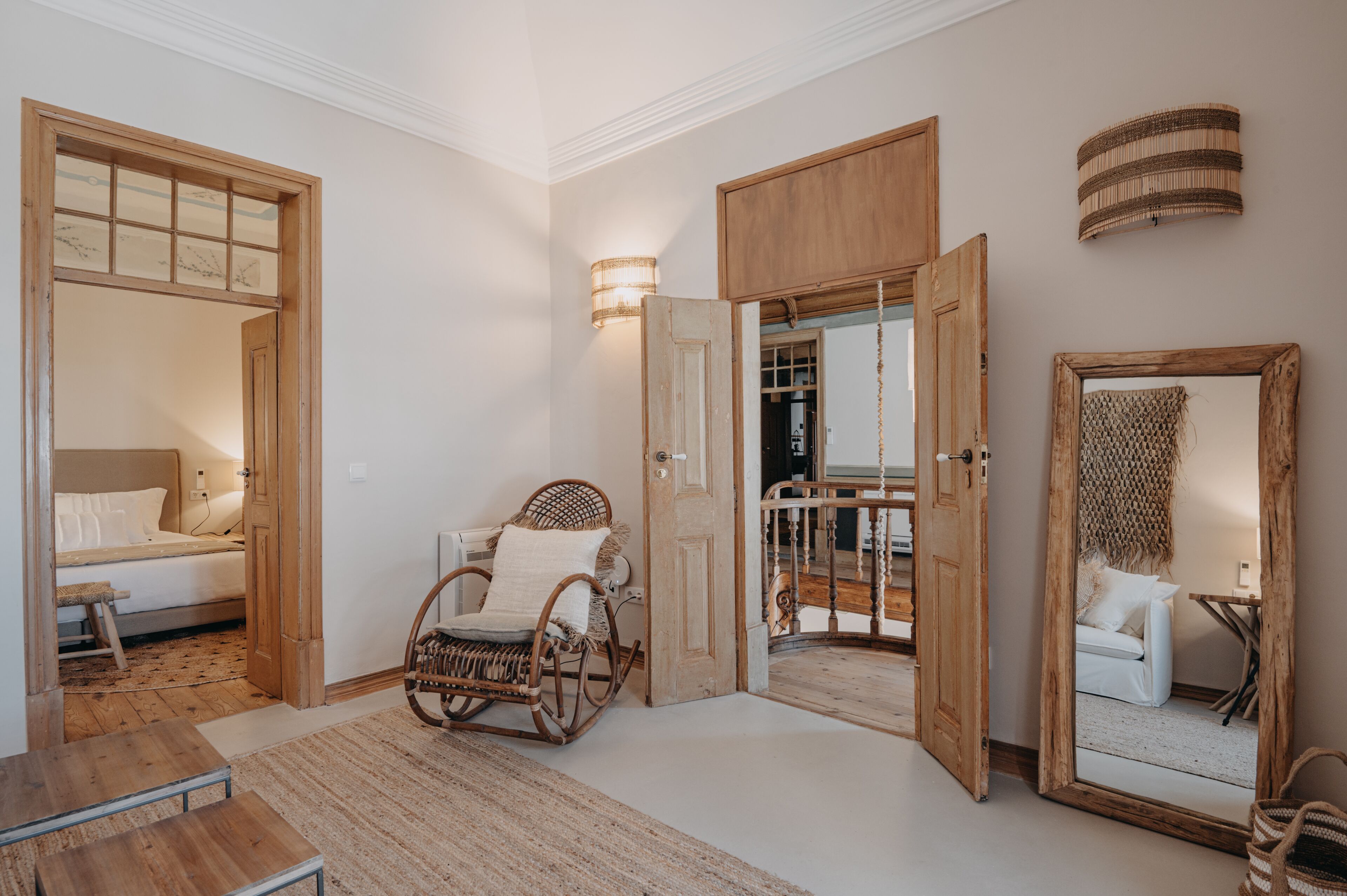 A spacious room with a large bed, a rocking chair, and a wooden door leading to another room.