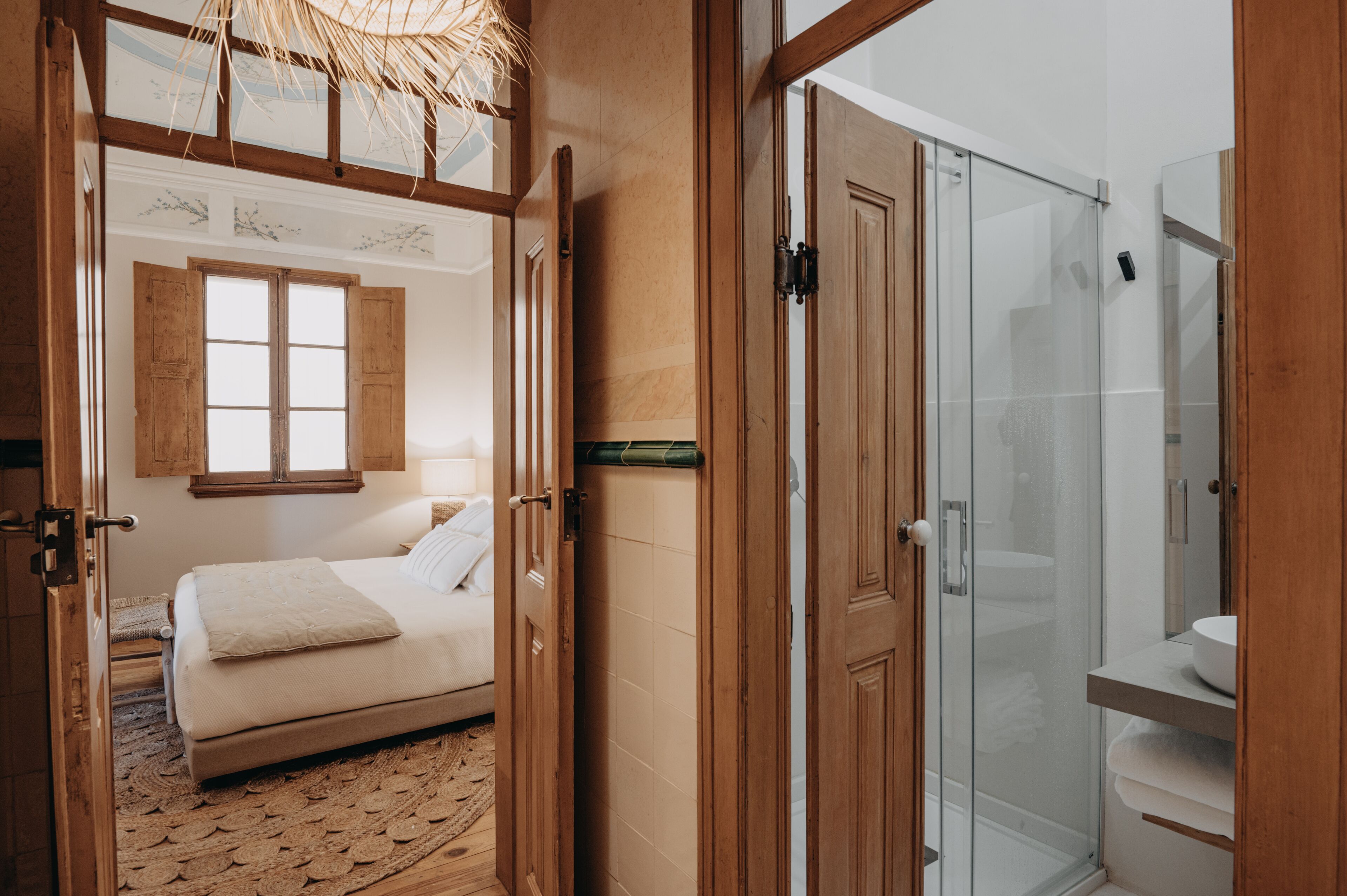 A bedroom with a bed, wooden wardrobe, and a glass shower enclosure.