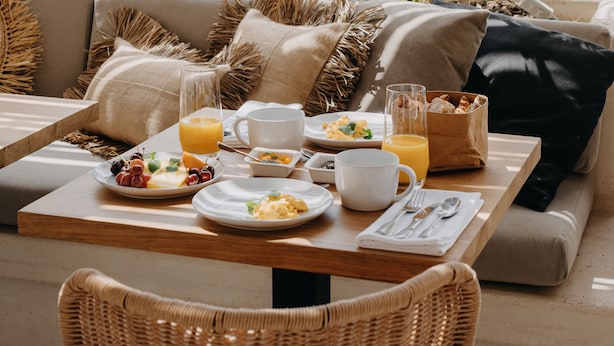 A breakfast setup with a table, wicker chairs, and a sofa with cushions. - Casa Az-Zagal (Sousel)