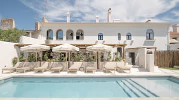 Relax by the pool surrounded by lush greenery and an outdoor seating area.