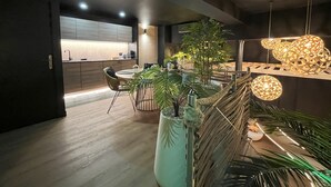 Une cuisine moderne avec des meubles en bois, un coin repas doté d’une table ronde et de chaises, et des luminaires décoratifs suspendus au plafond.