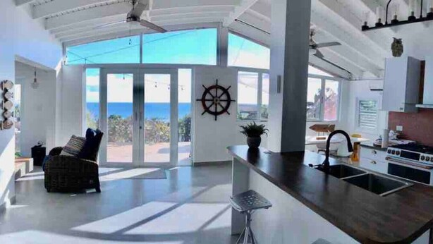 Une cuisine spacieuse dotée d’un grand îlot central, d’un coin repas offrant une vue agréable et d’une décoration sur le thème de la voile.