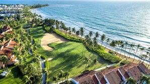 Un parcours de golf situé sur la côte, offrant une vue sur l’océan et les palmiers.