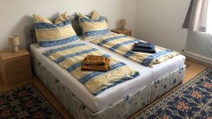 Una cama bien hecha con ropa de cama a rayas, dos mesitas de noche con lámparas y una alfombra estampada en el suelo.