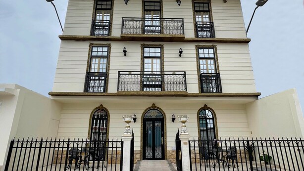 A multi-story building with a symmetrical facade, large windows with ornate iron railings, and a central entrance with a black door. - Hotel The Royalty Inn (Guayaquil)