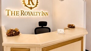A reception desk with a logo, a chandelier, and a black chair. - Hotel The Royalty Inn (Guayaquil)