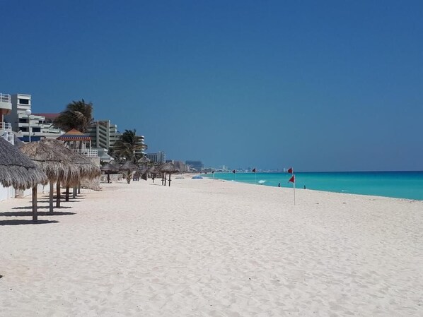 Playa privada, arena blanca, sillas reclinables de playa, sombrillas