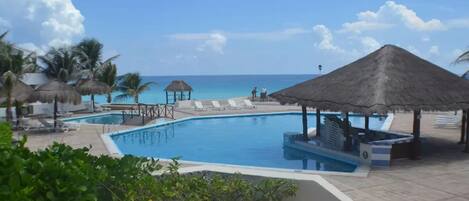 Alberca al aire libre, sombrillas en la alberca y camastros