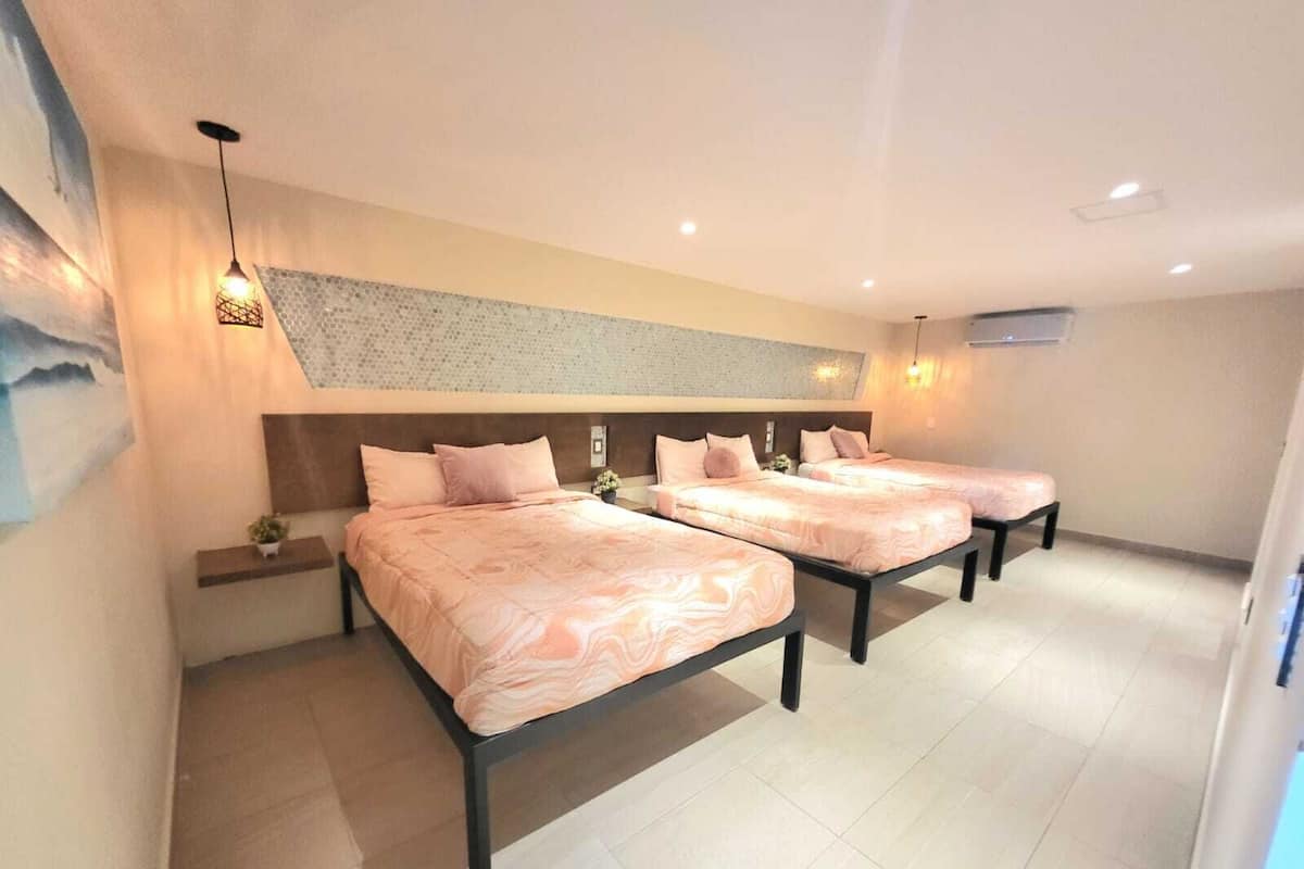 A hotel room with three beds, a large wall art piece, and a modern ceiling design.