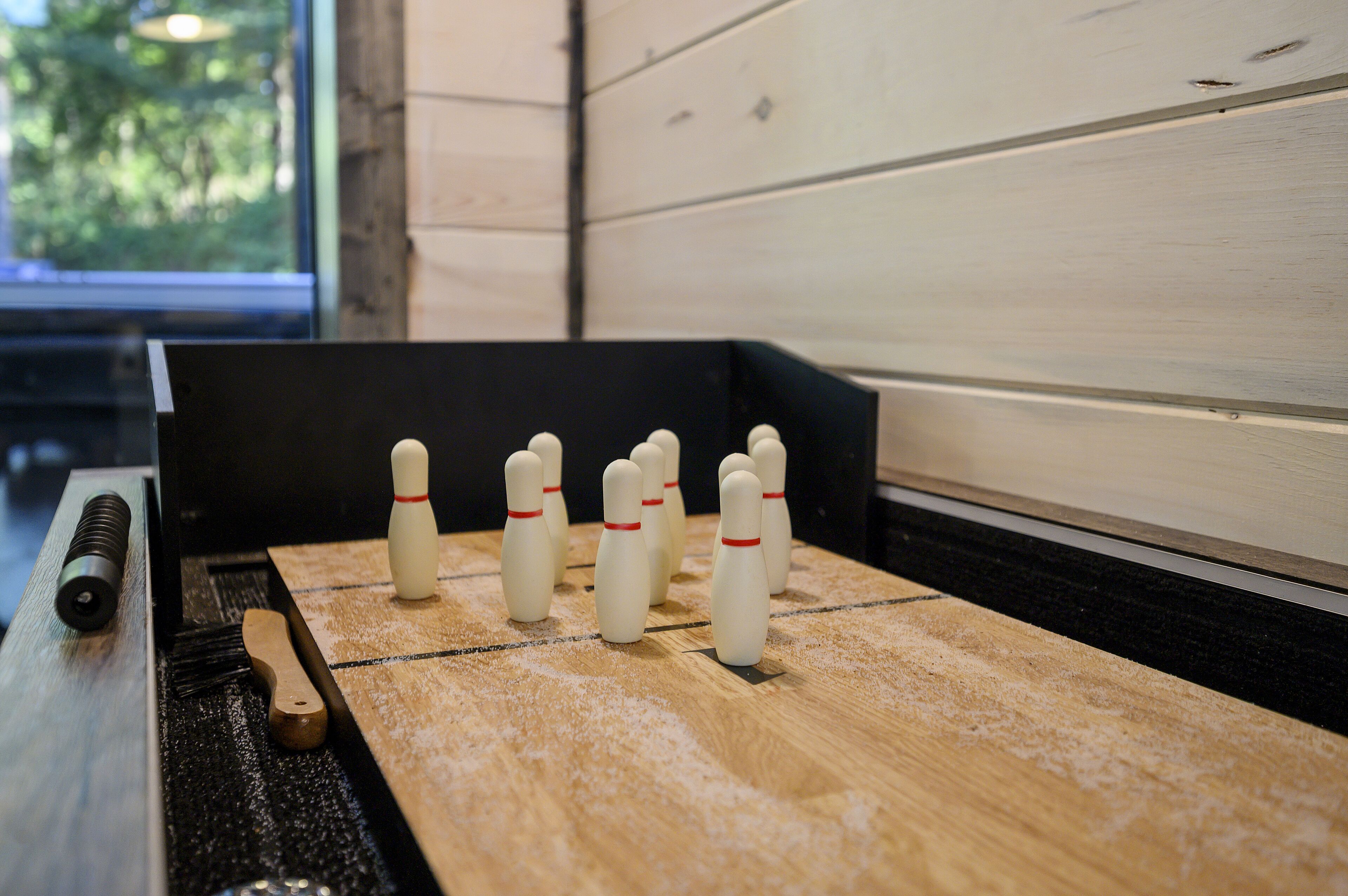 Eine Kegelbahn mit Holzboden und mehreren aufgestellten Bowlingkegeln.