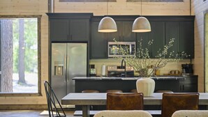 A modern kitchen with dark cabinets, a large island, and pendant lighting.